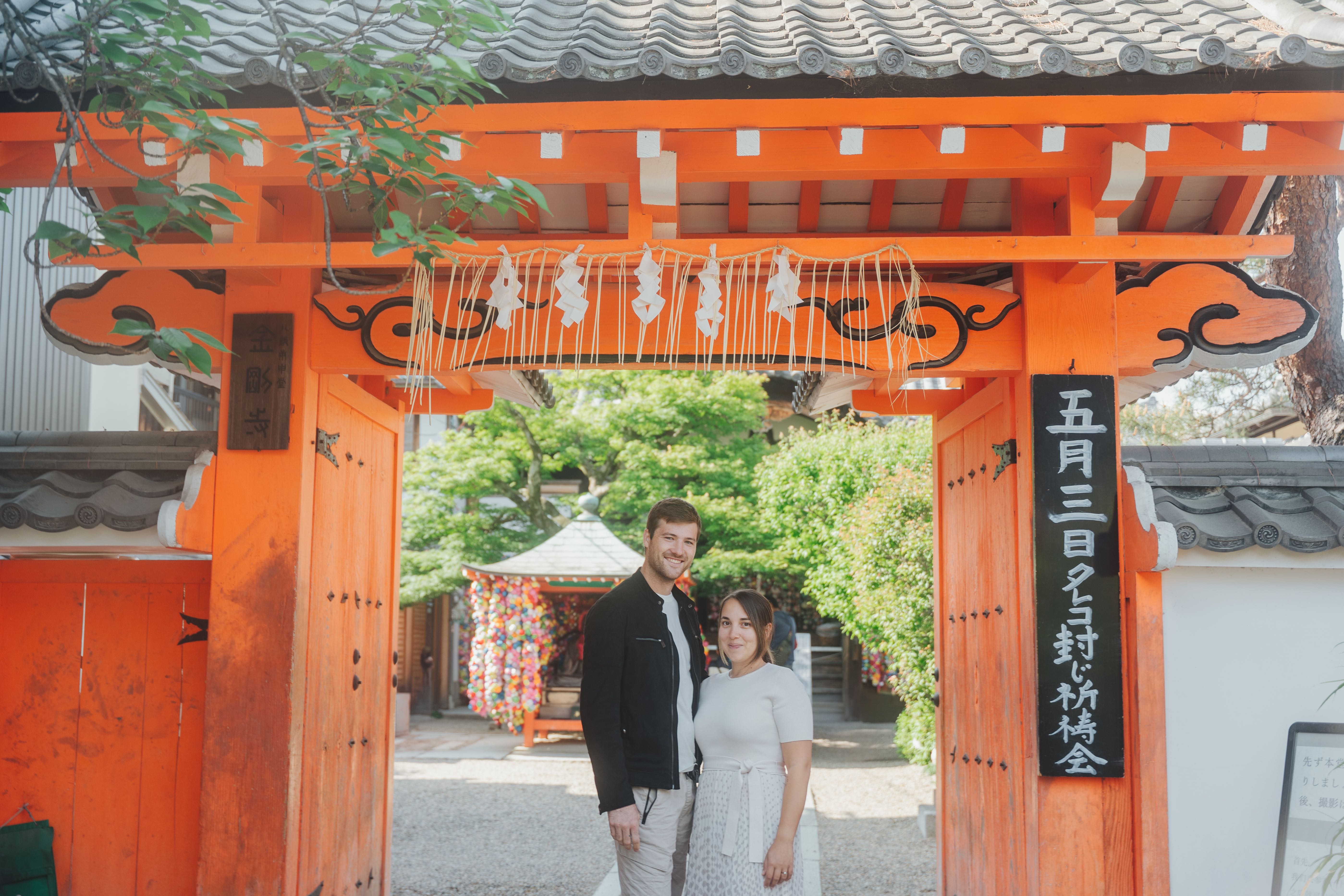 Couple under traditional orange torii gate at Japanese shrine